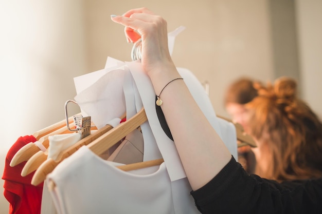 Immagine ritagliata di una donna che tiene i vestiti appesi ai ganci per i cappotti