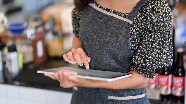 Immagine ritagliata di una giovane barista che prende l'ordine sul tablet al bar