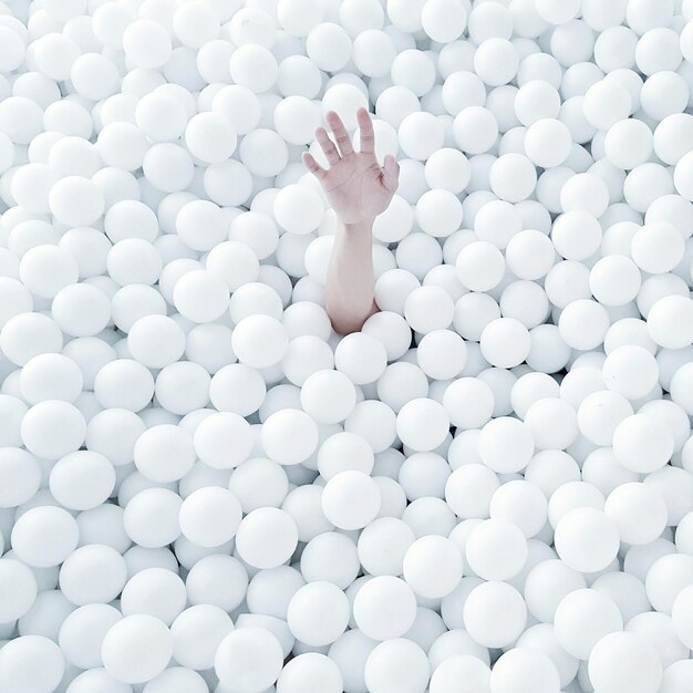 Immagine ritagliata di una mano che emette da una piscina di palle bianche