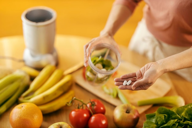 Immagine ritagliata di una mano che mostra pillole e cibo sano alla telecamera