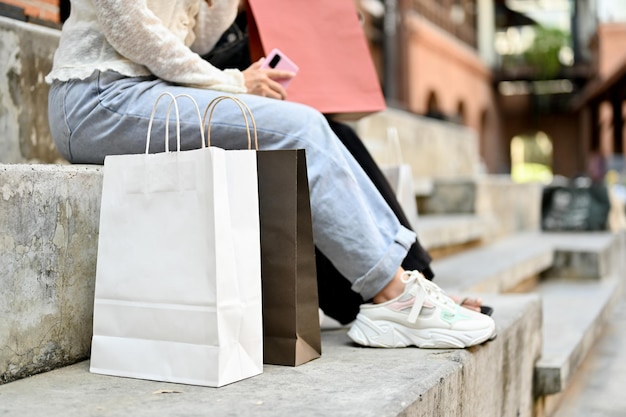 Immagine ritagliata Due amiche sedute sulle scale della strada con le borse della spesa