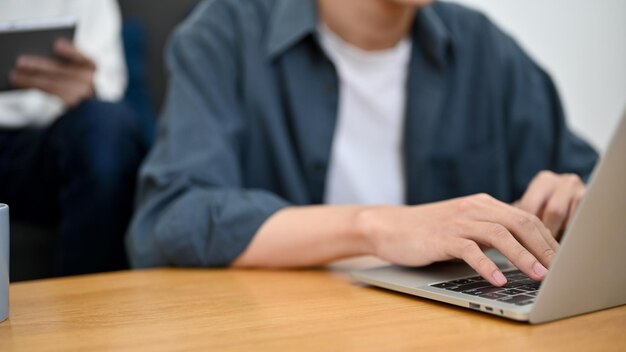 Immagine ritagliata Un libero professionista maschio o uno studente universitario che utilizza il laptop digitando sulla tastiera