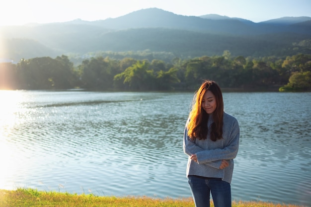 Immagine ritratto di una bella donna asiatica in piedi di fronte al lago e alle montagne prima del tramonto