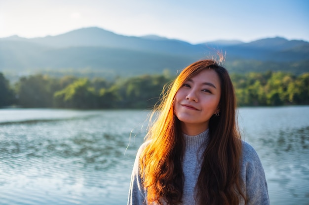 Immagine ritratto di una bella donna asiatica in piedi di fronte al lago e alle montagne prima del tramonto