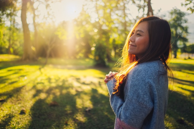 Immagine ritratto di una bella donna asiatica in piedi tra la natura nel parco prima del tramonto