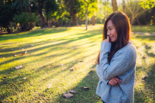 Immagine ritratto di una bella donna asiatica in piedi tra la natura nel parco prima del tramonto