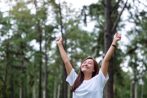 Immagine ritratto di una donna felice con le braccia in aumento nel parco