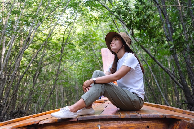 Immagine ritratto di una giovane e bella donna asiatica seduta su una barca a coda lunga mentre si viaggia nella foresta di mangrovie