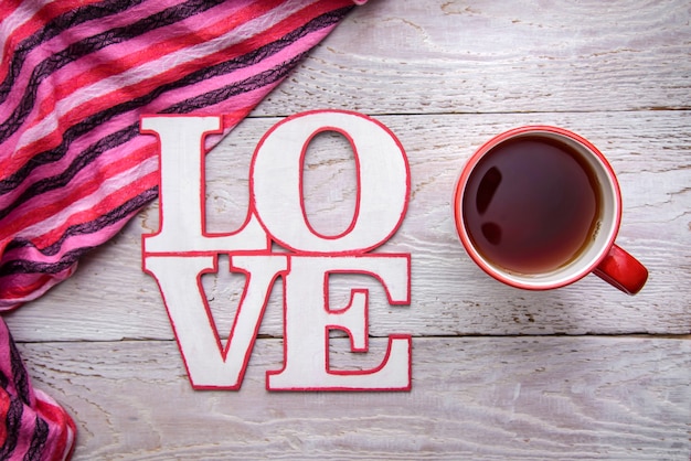 Immagine romantica semplice e carina con una tazza di tè e la parola AMORE su uno sfondo di legno per San Valentino