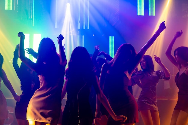 Immagine silhouette di persone ballano in discoteca night club alla musica di Dj sul palco