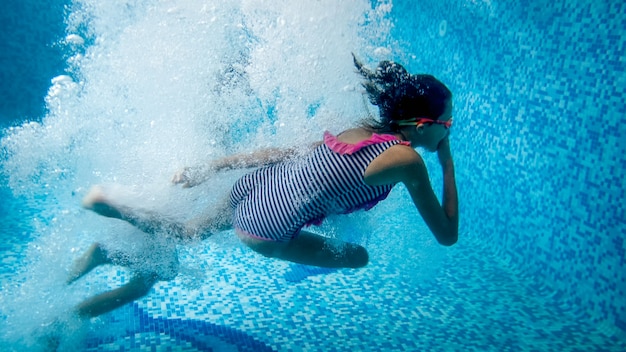 Immagine subacquea di due ragazze adolescenti che saltano in piscina al resort estivo dell'hotel