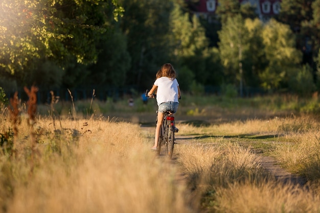 Immagine tonica della giovane donna che si allontana in bicicletta al prato