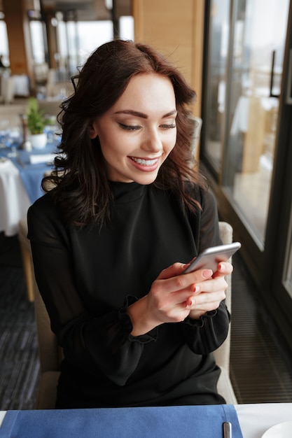 Immagine verticale della donna nel messaggio di scrittura del ristorante sul telefono