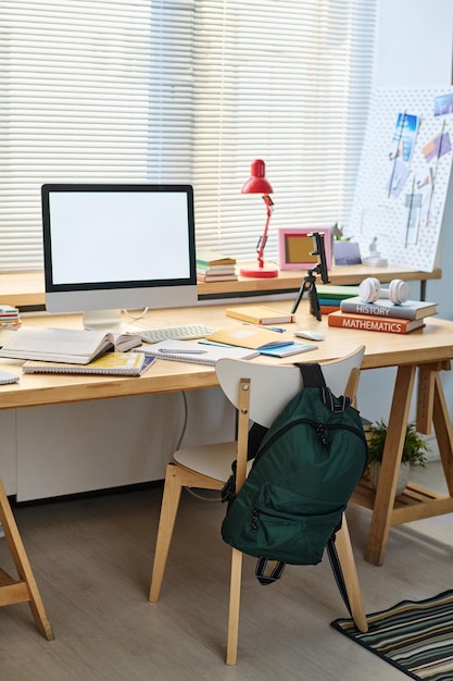 Immagine verticale della scrivania con il monitor del computer su di essa per lo studio online nella camera da letto dell'adolescente
