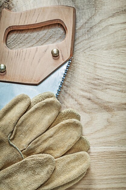 Immagine verticale di guanti di sicurezza in acciaio seghetto su tavola di legno concetto di costruzione