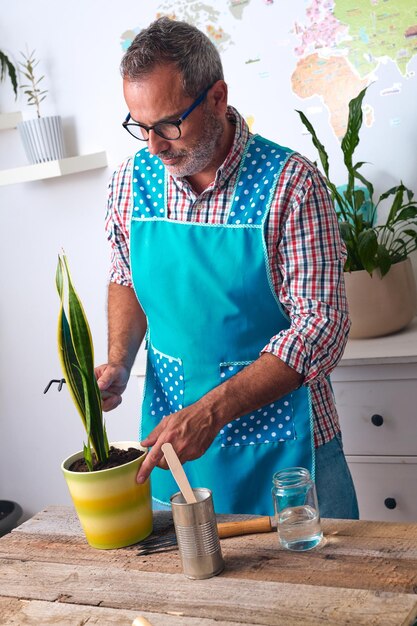 Immagine verticale di un uomo di mezza età che pianta una pianta in un concetto di sostenibilità di un vaso di fiori