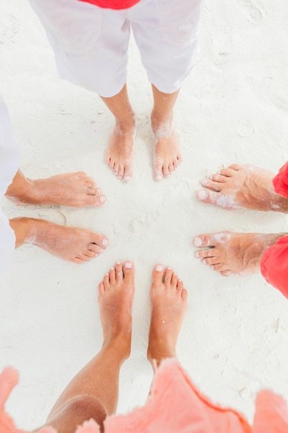 Immagine vista dall'alto dei piedi della famiglia in piedi sulla spiaggia di sabbia bianca.