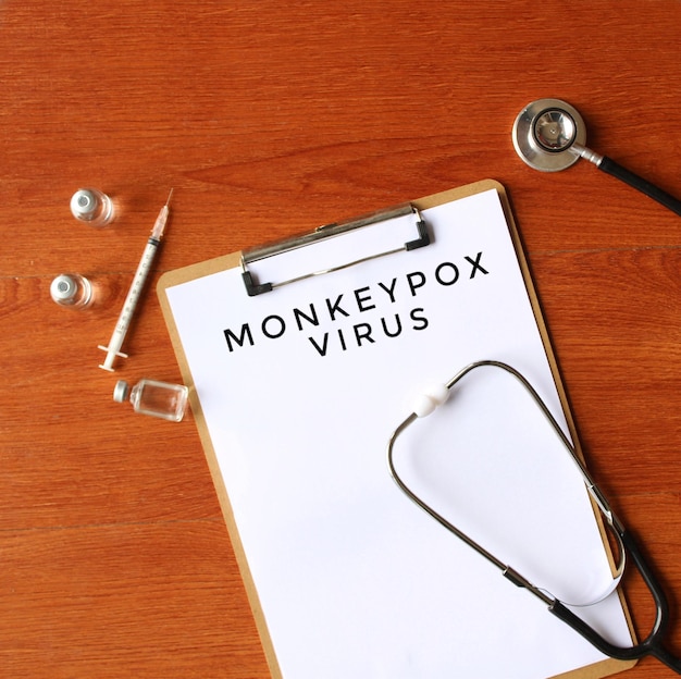 Immagine vista dall'alto della fiala di vetro dello stetoscopio e della carta con testo MONKEYPOX VIRUS Concetto medico