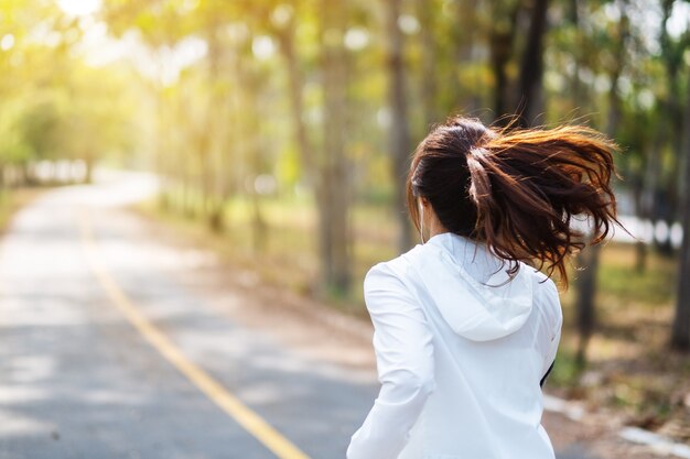 Immagine vista posteriore di una giovane donna asiatica che fa jogging nel parco cittadino al mattino