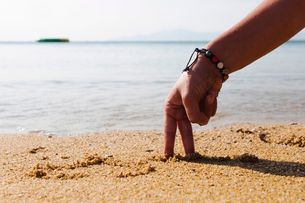 Immagini concettuali - mano sotto forma di uomo sulla spiaggia all'alba