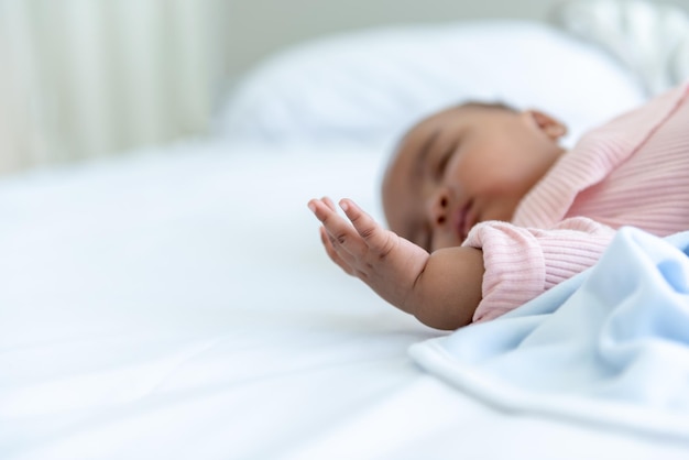 Immagini morbide sfocate di un neonato africano che dorme e giace su un letto bianco