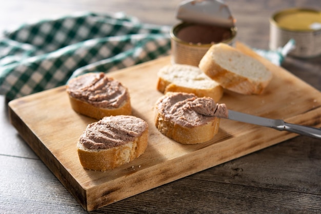 Immergere pane tostato con patè di fegato di maiale su tavola di legno