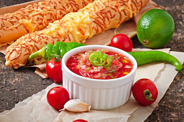 Immersione della salsa in ciotola di pane e bastoncini di formaggio su fondo di legno