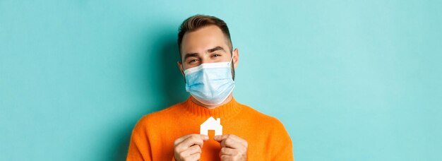 Immobiliare e concetto di pandemia di coronavirus primo piano di un uomo adulto in maschera medica che tiene un piccolo pape