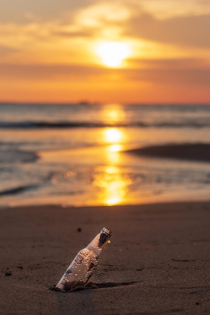 Immondizia di bottiglia di vetro sulla spiaggia sullo sfondo del tramonto Ecologia Inquinamento ambientale e concetto di problema ecologico