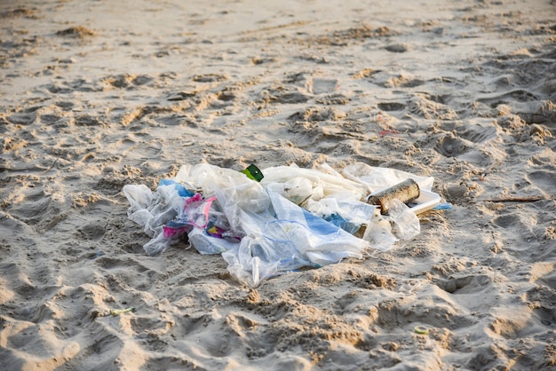 Immondizia nel mare con la bottiglia di plastica della borsa e l&#39;altra spiaggia sabbiosa dell&#39;immondizia