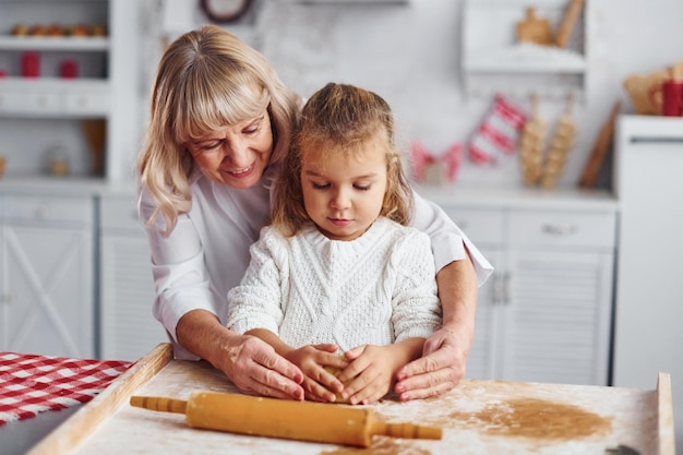 Impasta la pasta La nonna anziana con la sua nipotina cucina dolci per Natale in cucina