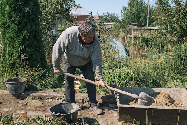 Impastare il cemento per versare il percorso del giardino, lavori di costruzione del giardino.