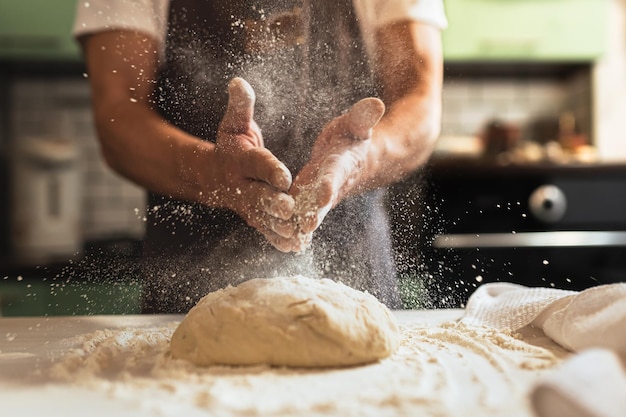 Impastare lo chef maschio in cucina grembiule dello chef spruzzare farina sopra l'impasto