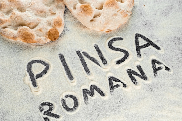 Impasto e farina con testo pinsa romana italiano su sfondo nero. Scrocchiarella cucina italiana gourmet. Piatto tradizionale in Italia.