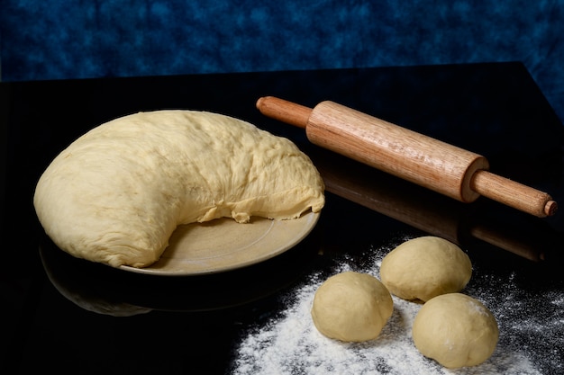 Impasto per la preparazione di pane e biscotti, appoggiato su una superficie scura e riflettente