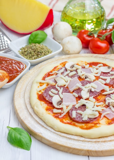 Impasto per pizza con salame, pancetta, funghi e formaggio