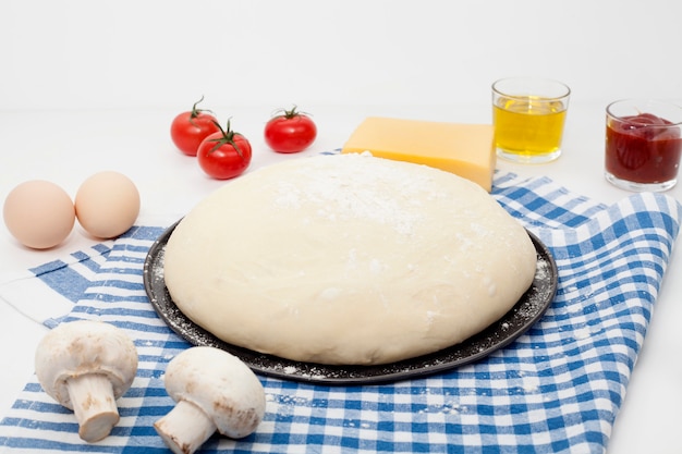 Impasto su un tavolo bianco, su un tovagliolo da cucina blu, con olio d'oliva, sale e pepe e panna acida