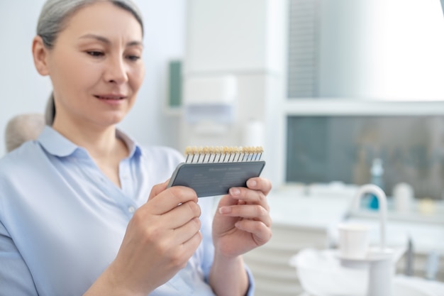 Impianti dentali. Donna seduta nell'ufficio del dentista e guardando gli impianti dentali