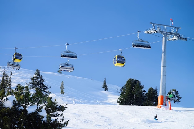 Impianti di risalita nel comprensorio sciistico di Penken nella Zillertal in Tirolo. Mayrhofen in Austria in inverno nelle Alpi. Funivie passeggeri alle montagne alpine con neve. Cielo azzurro e pendii bianchi e foresta.