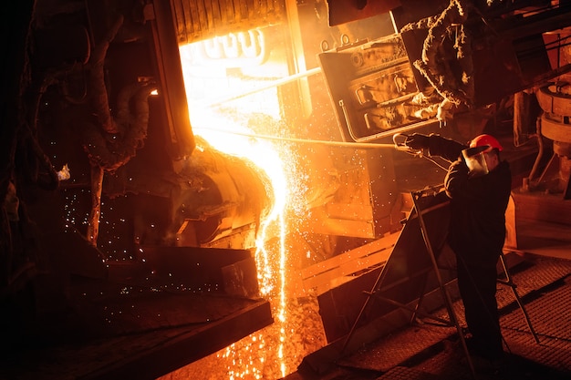 Impianto per la produzione di acciaio. Un forno di fusione elettrico. L'operaio preleva un campione di metallo.