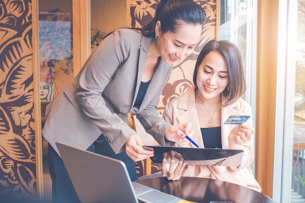 Impiegata femminile che spiega l'utilizzo della carta di credito ai clienti. I clienti soddisfatti sulla scrivania hanno computer e telefoni.