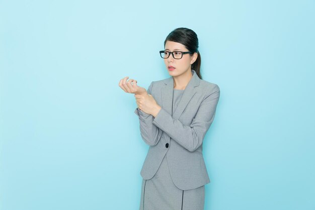 impiegato abbastanza di successo che lavora a lungo sentendosi doloroso al polso e ottenendo un infortunio sul lavoro che mostra sullo sfondo blu della parete.