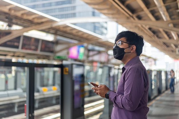 Impiegato aziendale che utilizza lo smartphone, in attesa che lo sky train vada in ufficio per lavorare