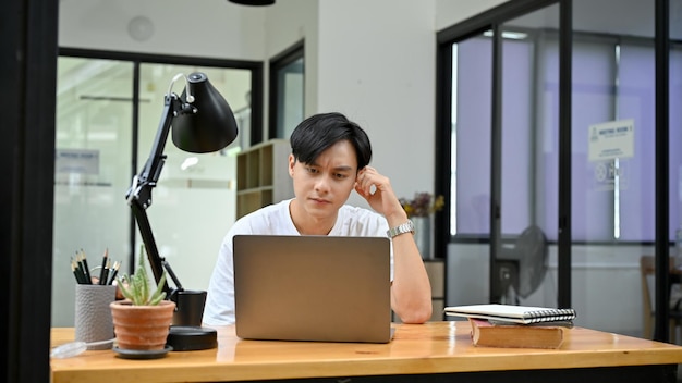 Impiegato d'ufficio maschio asiatico bello o studente universitario confuso con il suo incarico