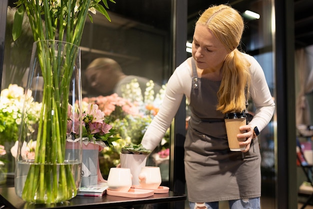 Impiegato del negozio di fiori nel processo di lavoro accanto a un frigorifero con fiori