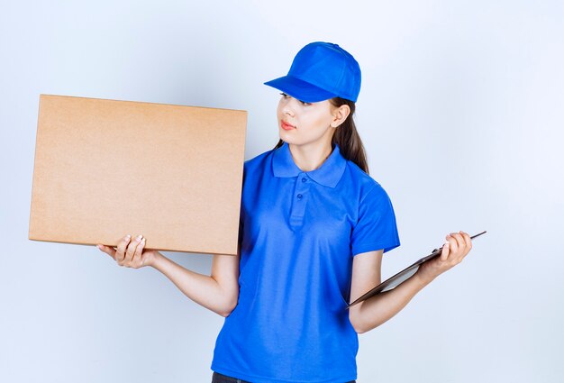 Impiegato della donna di consegna in scatola di carta del mestiere della tenuta dell'uniforme con la cartella.