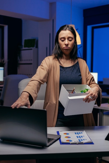 Impiegato depresso dopo essere stato licenziato con cardbox in mano. Donna triste che tiene le sue cose a tarda notte in ufficio dopo essere stata licenziata dal lavoro. Imprenditrice licenziata, crisi economica