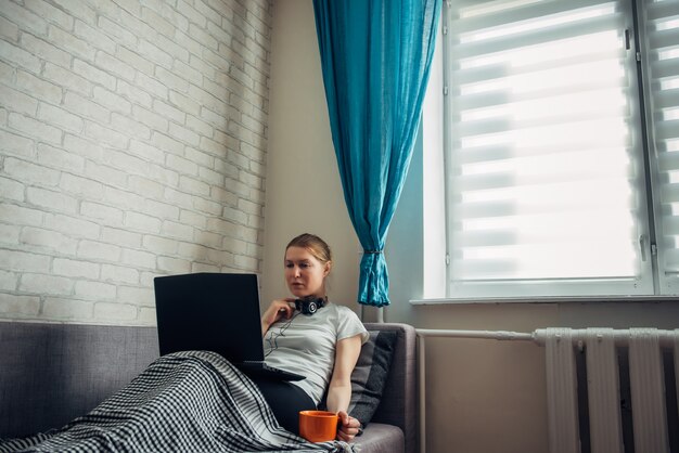 Impiegato di giovane donna con il computer portatile nell'isolamento di sé che lavora dalla casa