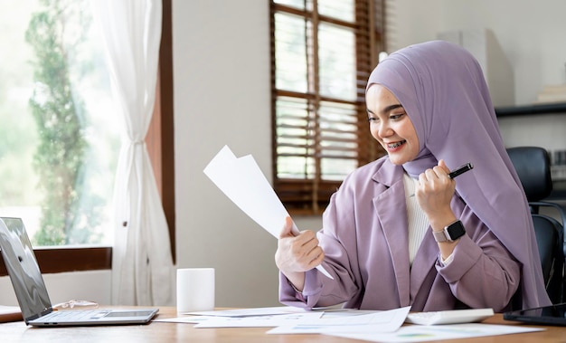 Impiegato di ufficio giovane bella donna araba gioiosa sorridente mentre si lavora con il computer portatile in ufficio