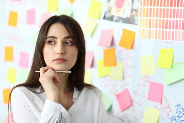 Impiegato femminile grazioso che sta nell'ufficio che risolve compito difficile